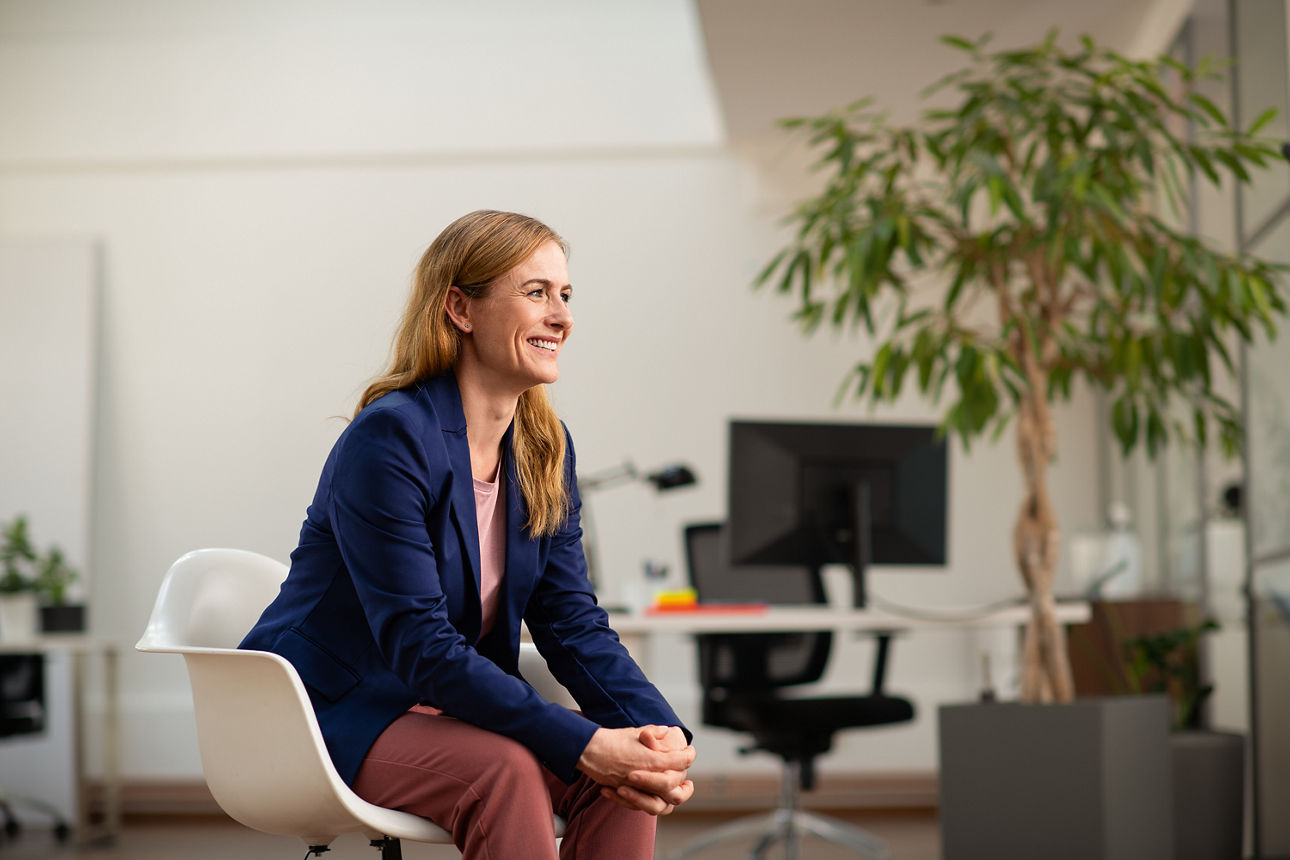 Eine Frau sitzt in einem modernen Büro und schaut zur Seite