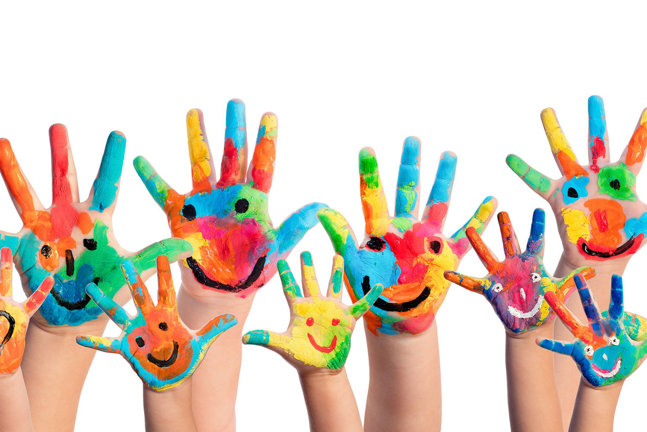 Bunte Kinderhände mit einem aufgemalten Gesicht