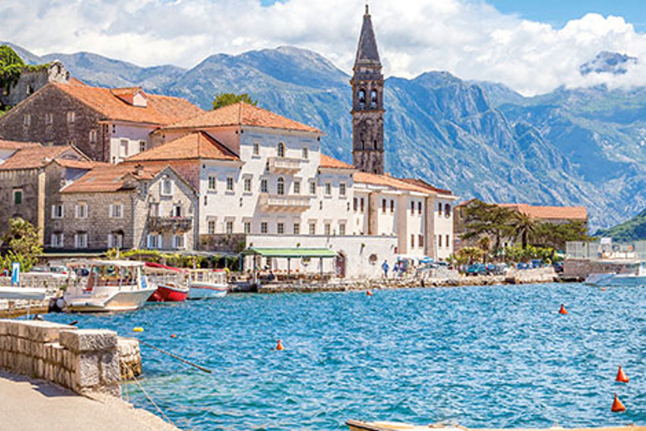 Historische Altstadt von Kotor an der Adria: Mittelalterliche Architektur und Glockenturm vor schroffer Berglandschaft.