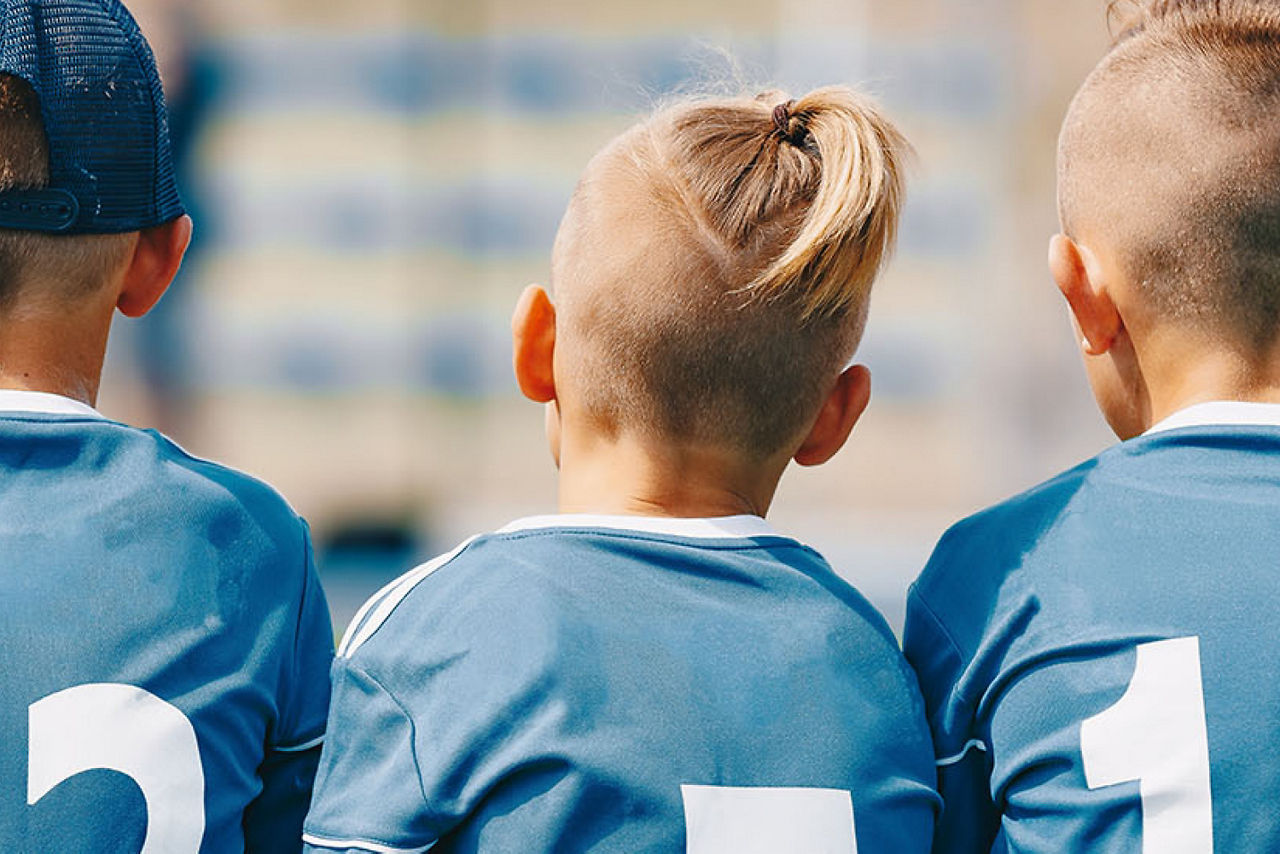 Drei Kinder die ein Fußballtrikot tragen