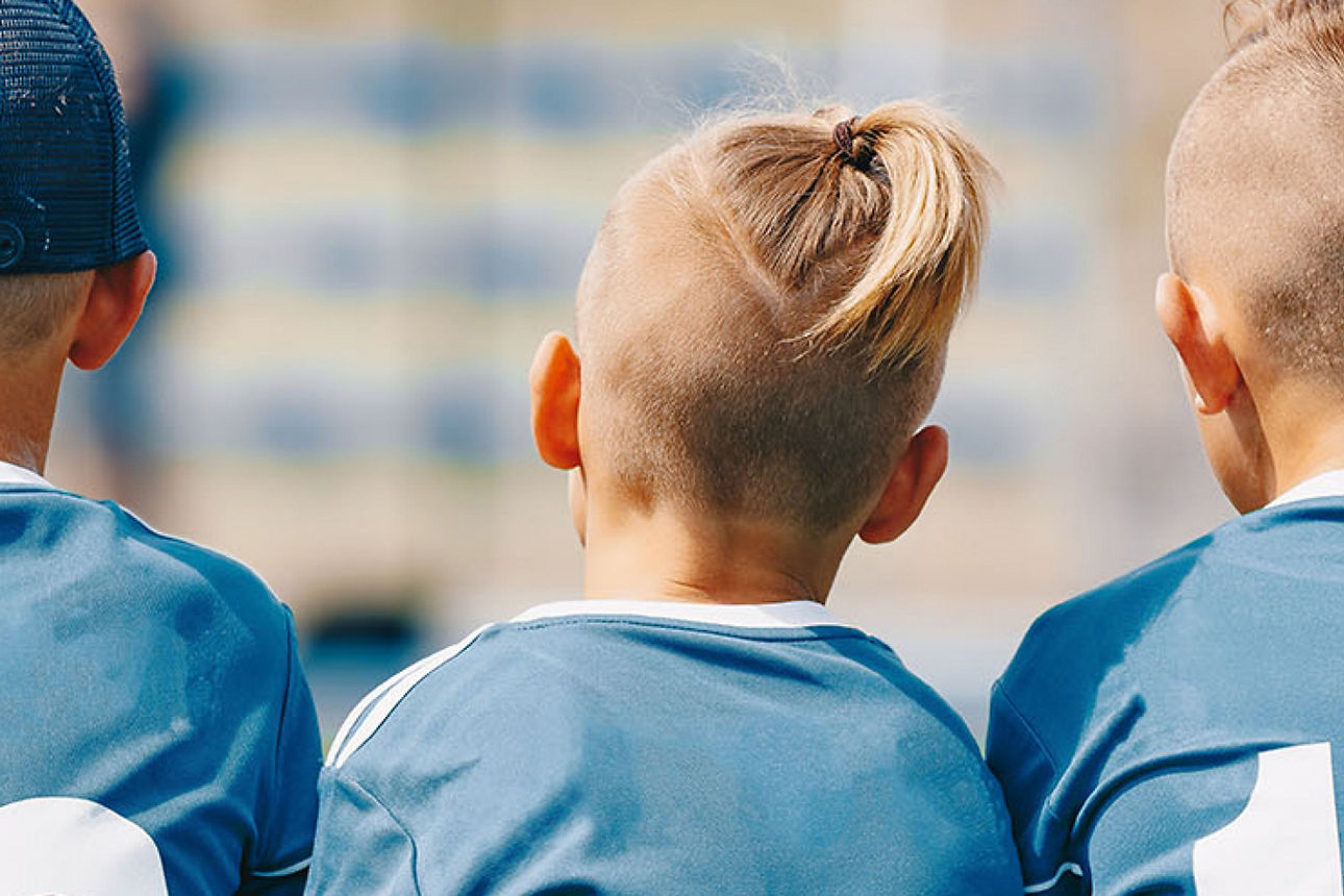 Drei Kinder die ein Fußballtrikot tragen