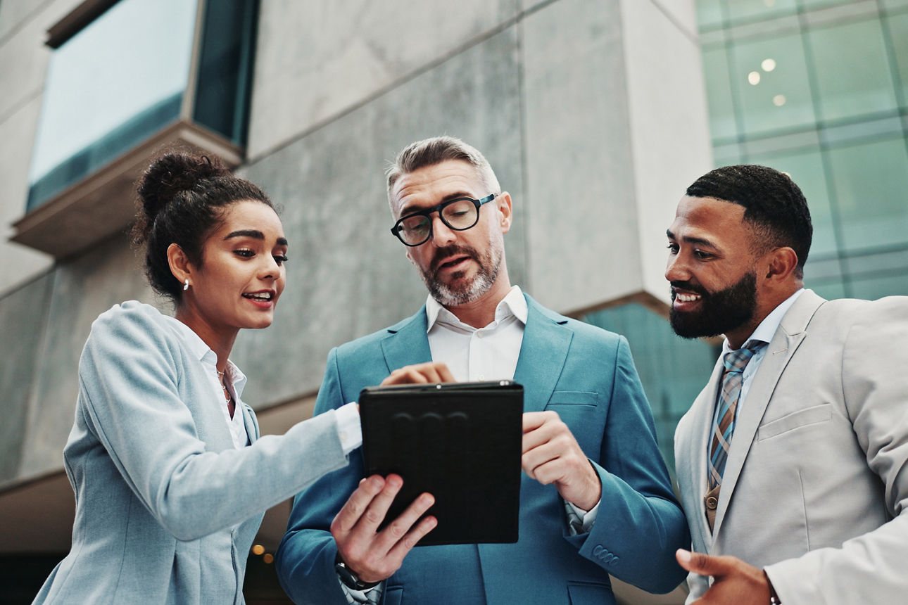 Drei Geschäftsleute lesen auf einem Tablet