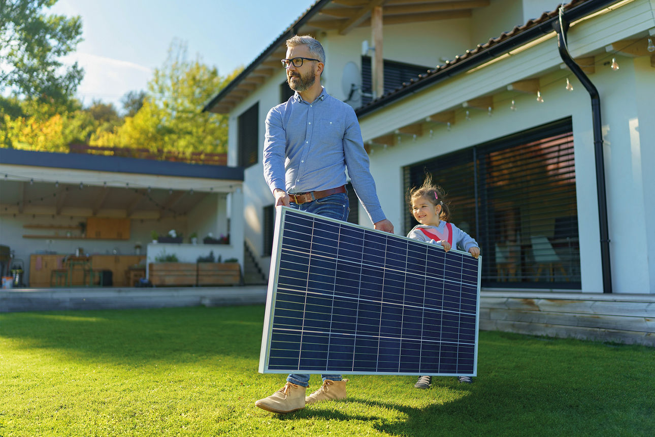 Mann mit Kind trägt ein Solar-Panel