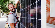 Ein Mann trägt ein Photovoltaikmodul