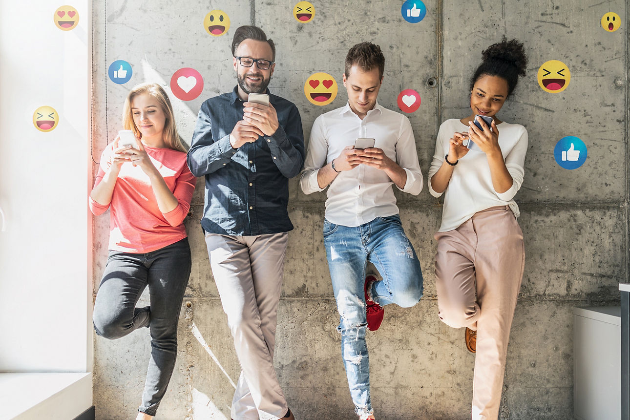 4 Personen mit Smartphones stehen an einer Wand. Um die Personen kreisen verschiedene Emojis