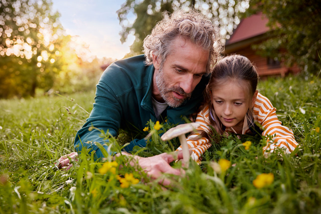 Vater und Tochter liegen auf einer Wiese in der Natur