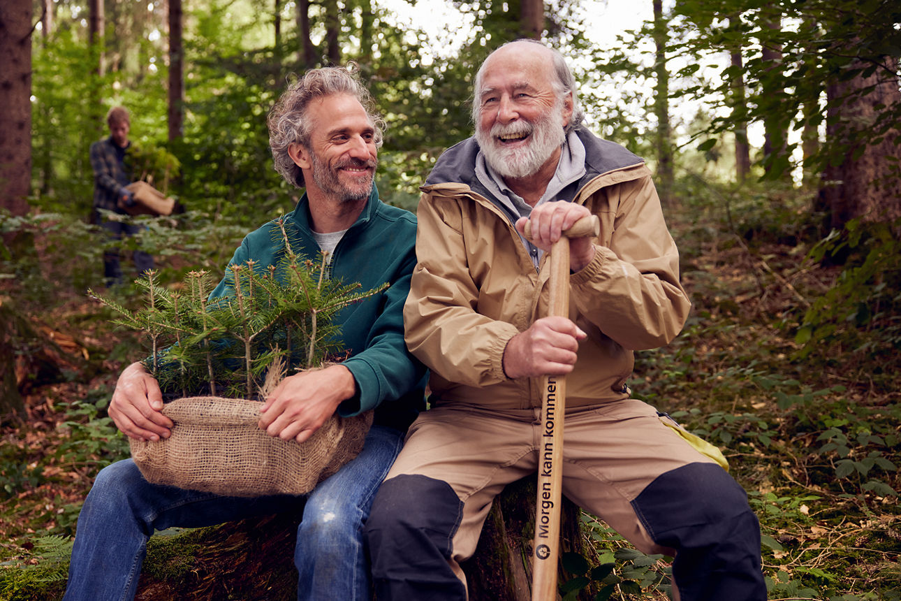 Zwei Männer mit Bart sitzen im Wald mit Sprößlingen