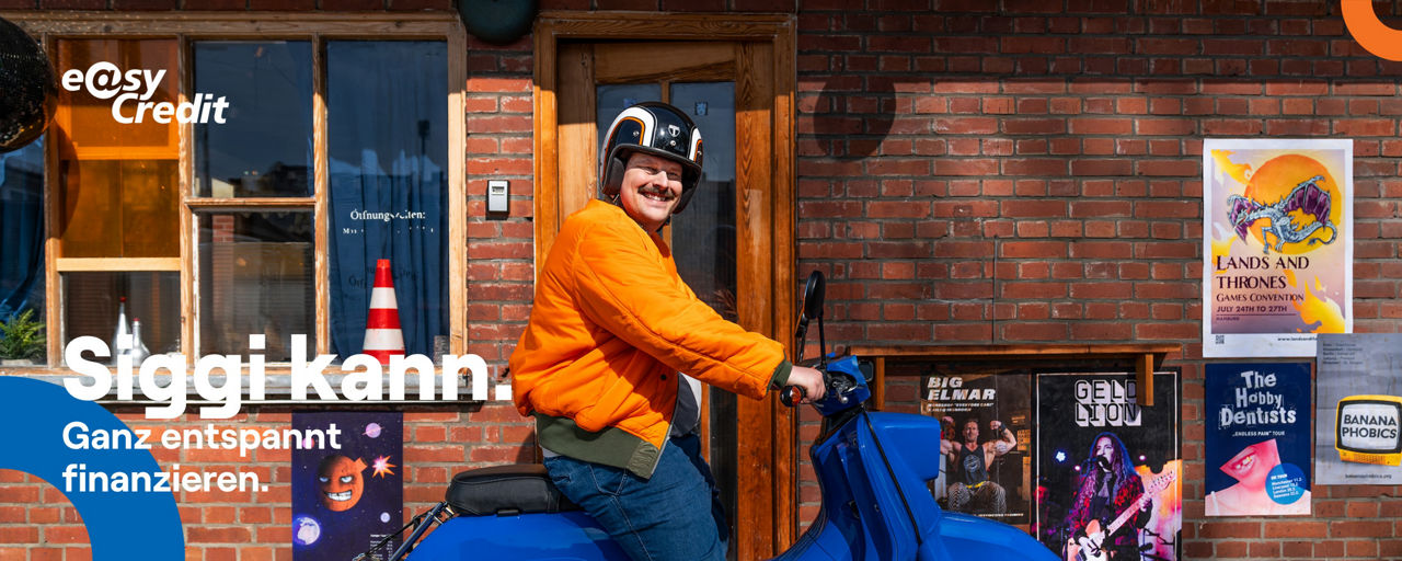 Mann sitzt in orangener Jacke auf blauem Moped und lacht in die Kamera. Auf dem Bild steht der Schriftzug "Siggi kann".