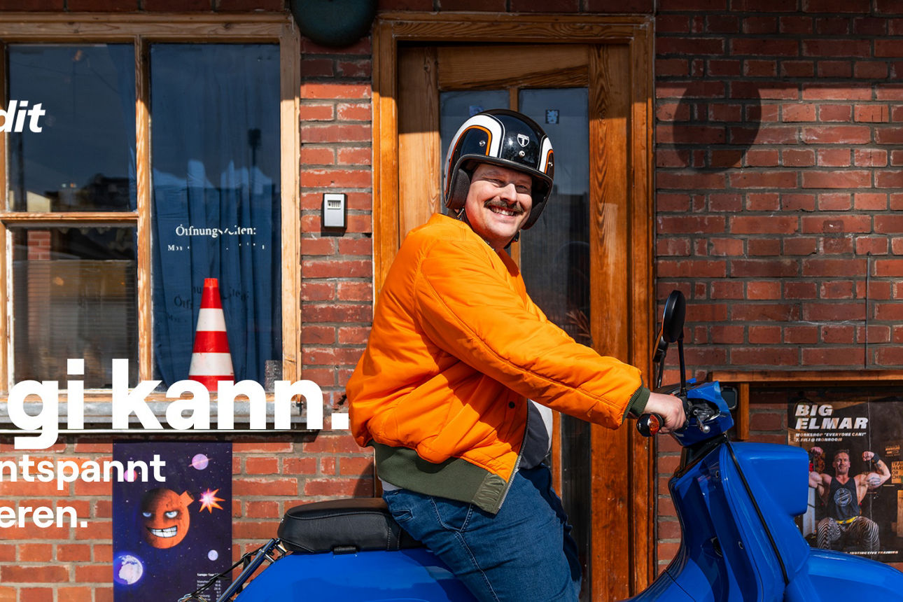 Mann sitzt in orangener Jacke auf blauem Moped und lacht in die Kamera. Auf dem Bild steht der Schriftzug "Siggi kann".