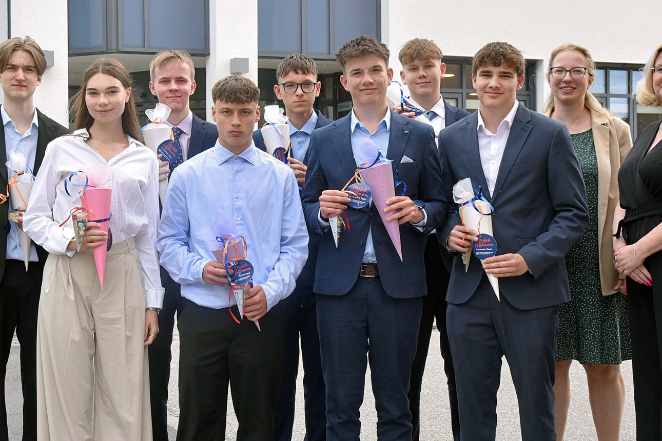 Eine stolze Gruppe von Absolventen in festlicher Kleidung posiert mit bunten Eistüten voller Leckereien.