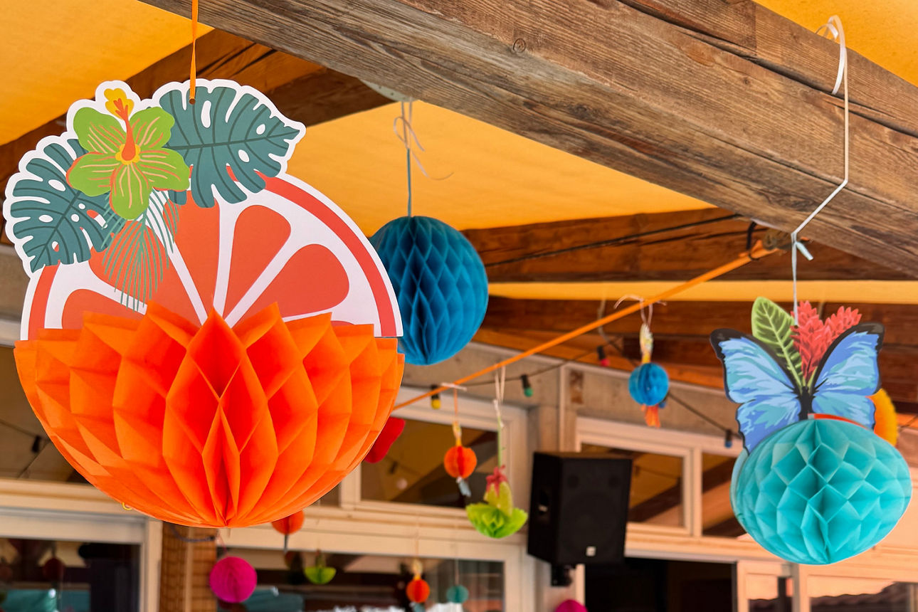 Kräftige Papierdekorationen in Orange und Teal schmücken den Raum.