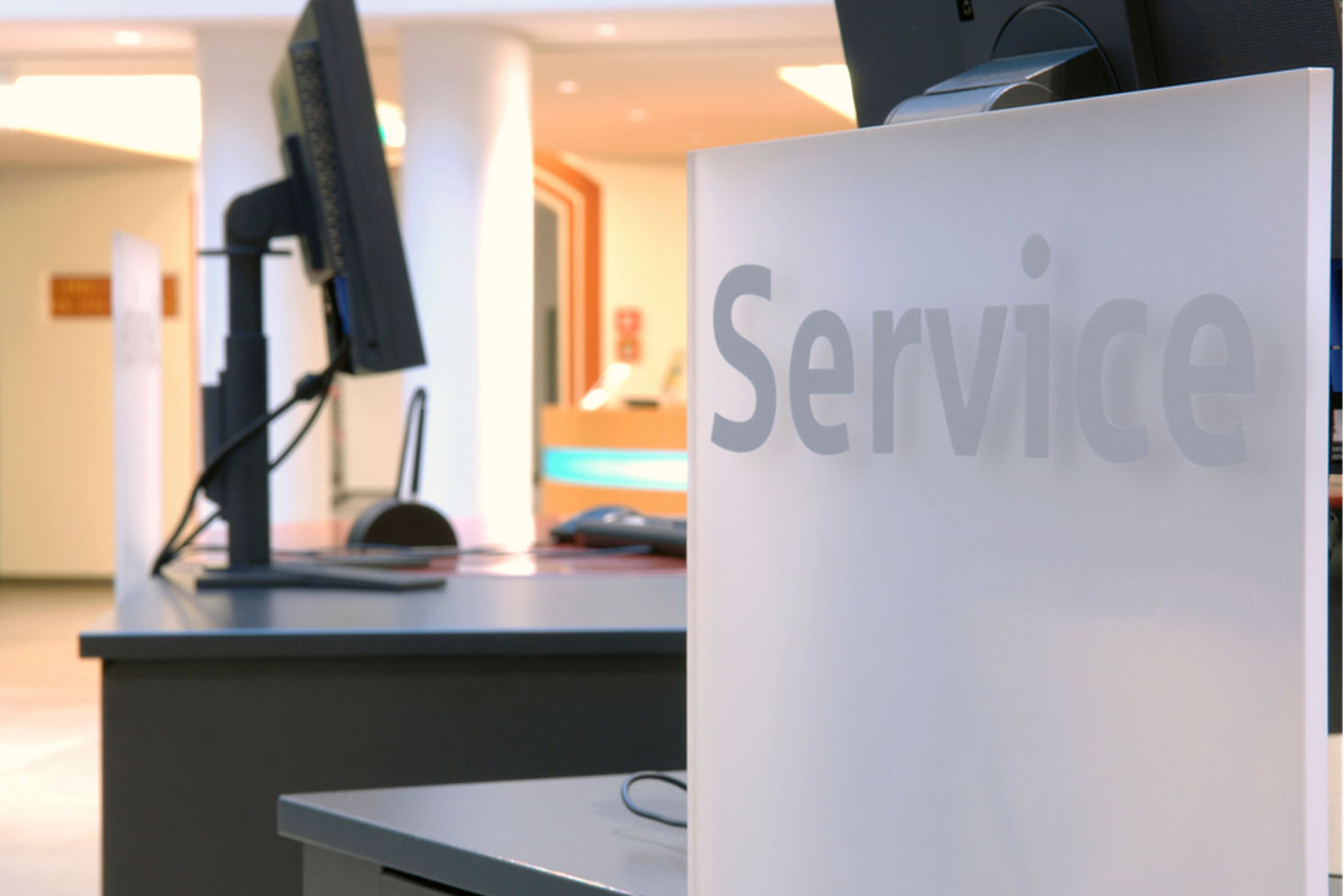 Schalter einer Bankfiliale mit Schild auf dem Service steht