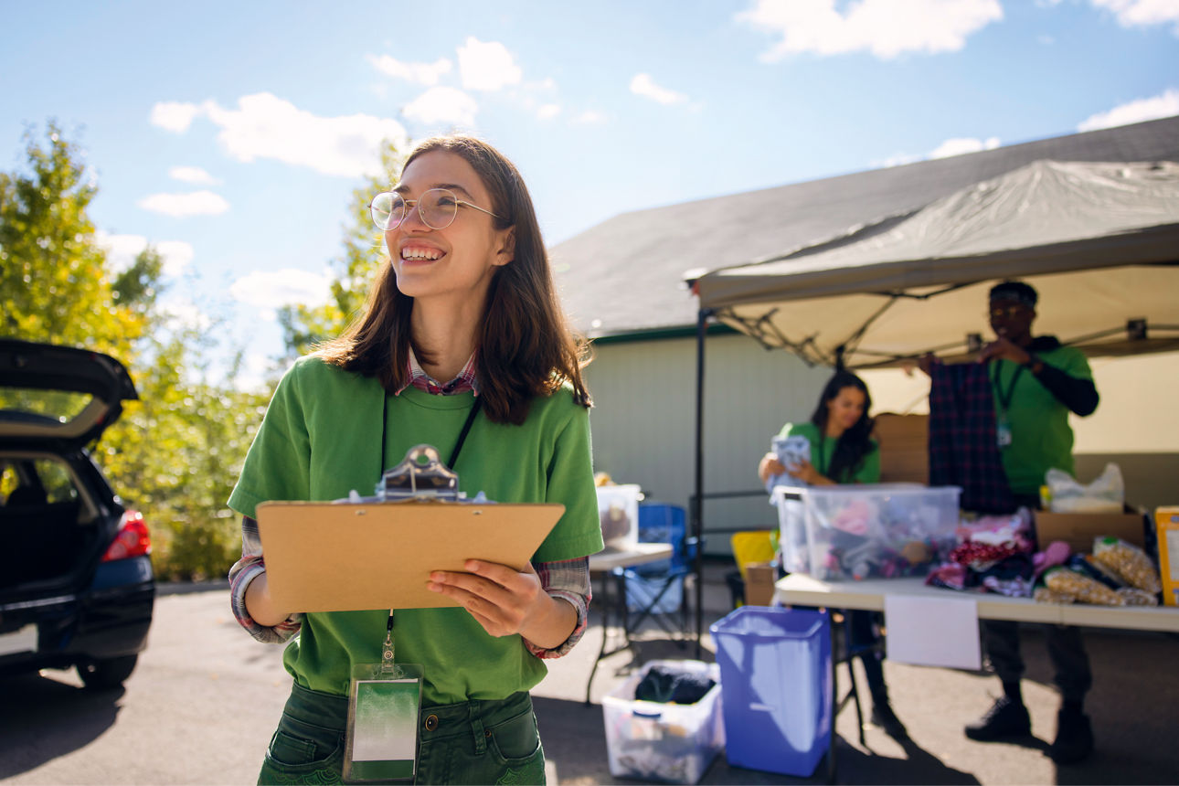 Frauen, die ein Klemmbrett halten und mit einem Lächeln aus dem Bild schauen