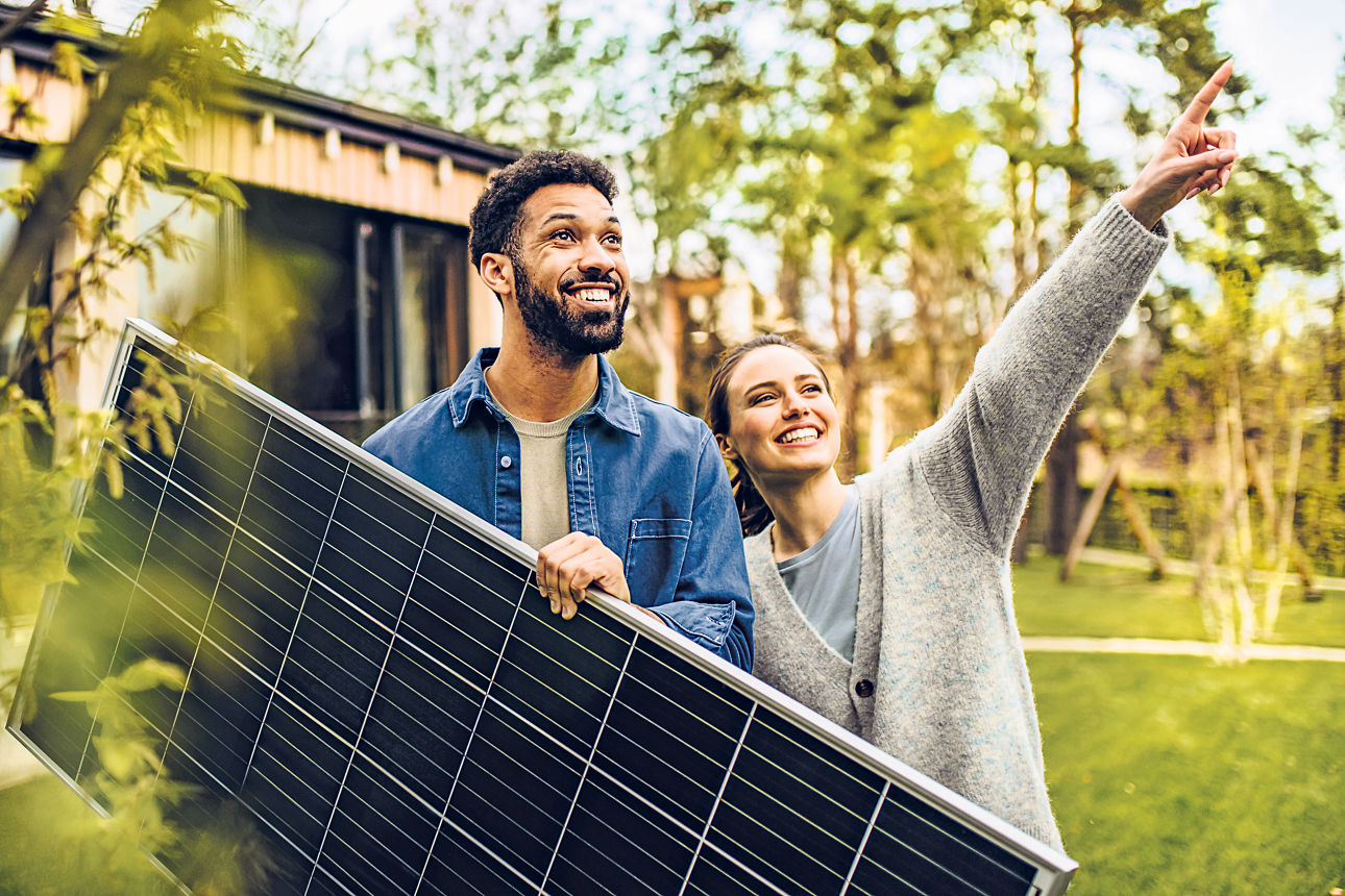 Ein Mann und eine Frau stehen im Garten mit einem Solarpanel in der Hand