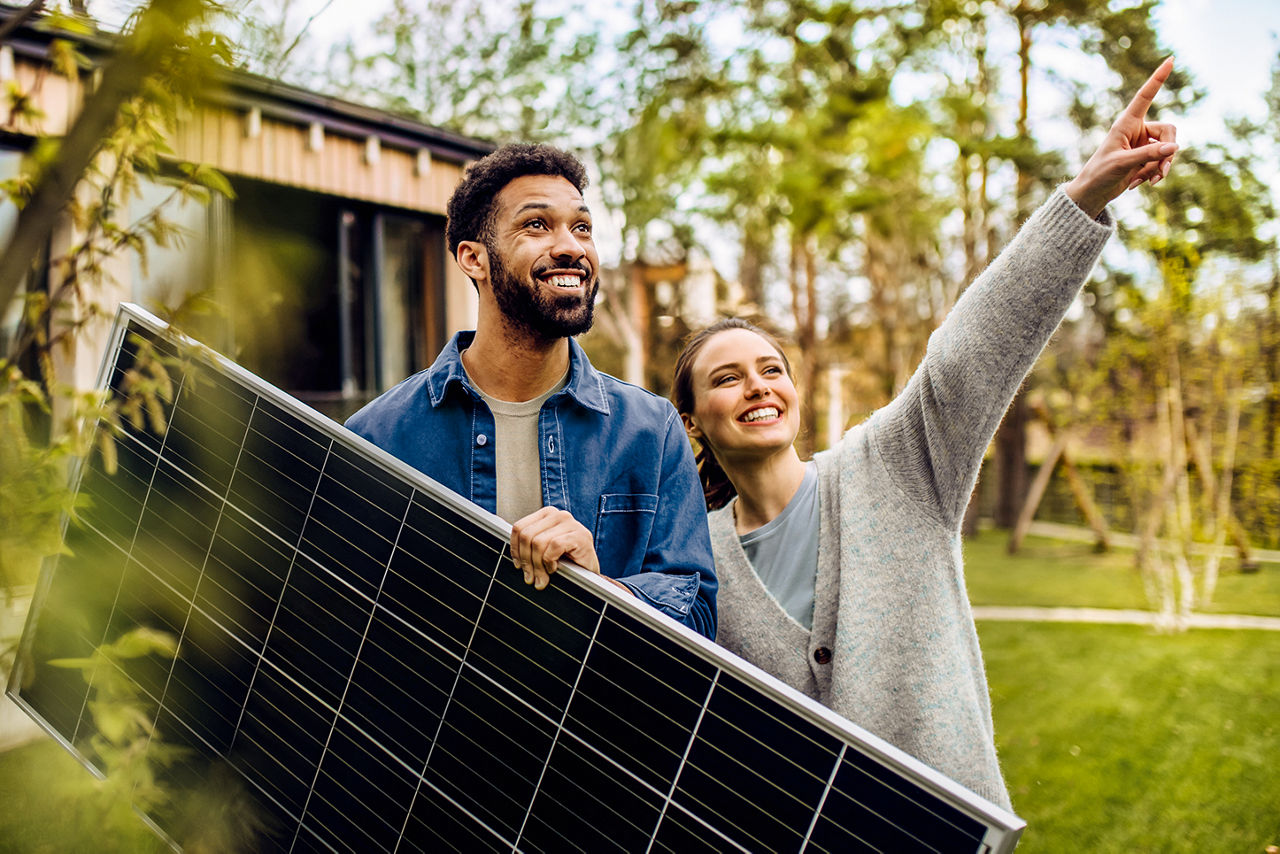 Paar mit Solarpanel in der Hand schaut nach oben
