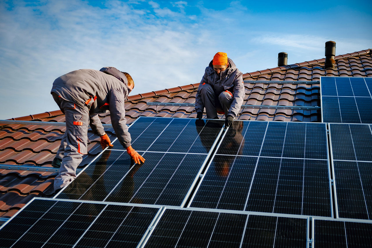 Zwei Männer auf dem Dach die Solarzellen anbringen