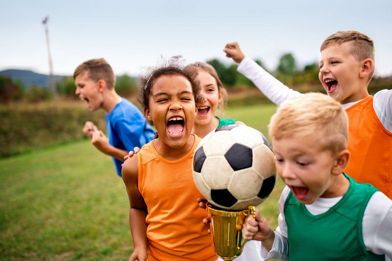 Gruppe jubelnder Kinder mit Pokal feiert einen Sieg.