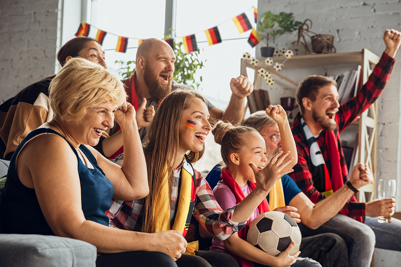 Eine aufgeregte, glückliche Großfamilie schaut Fußball auf dem Sofa zu Hause.