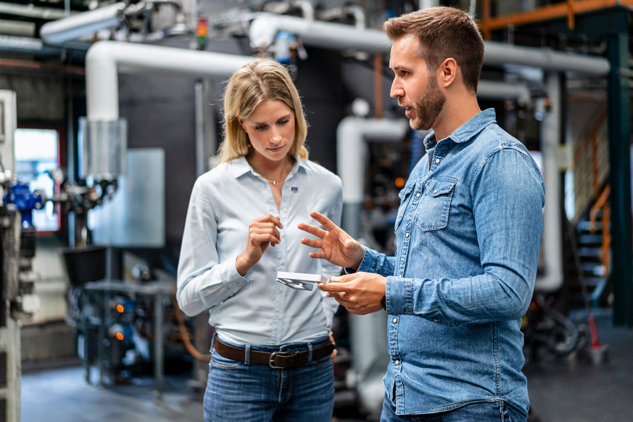 Frau und Mann im Gespräch in einer Produktionshalle