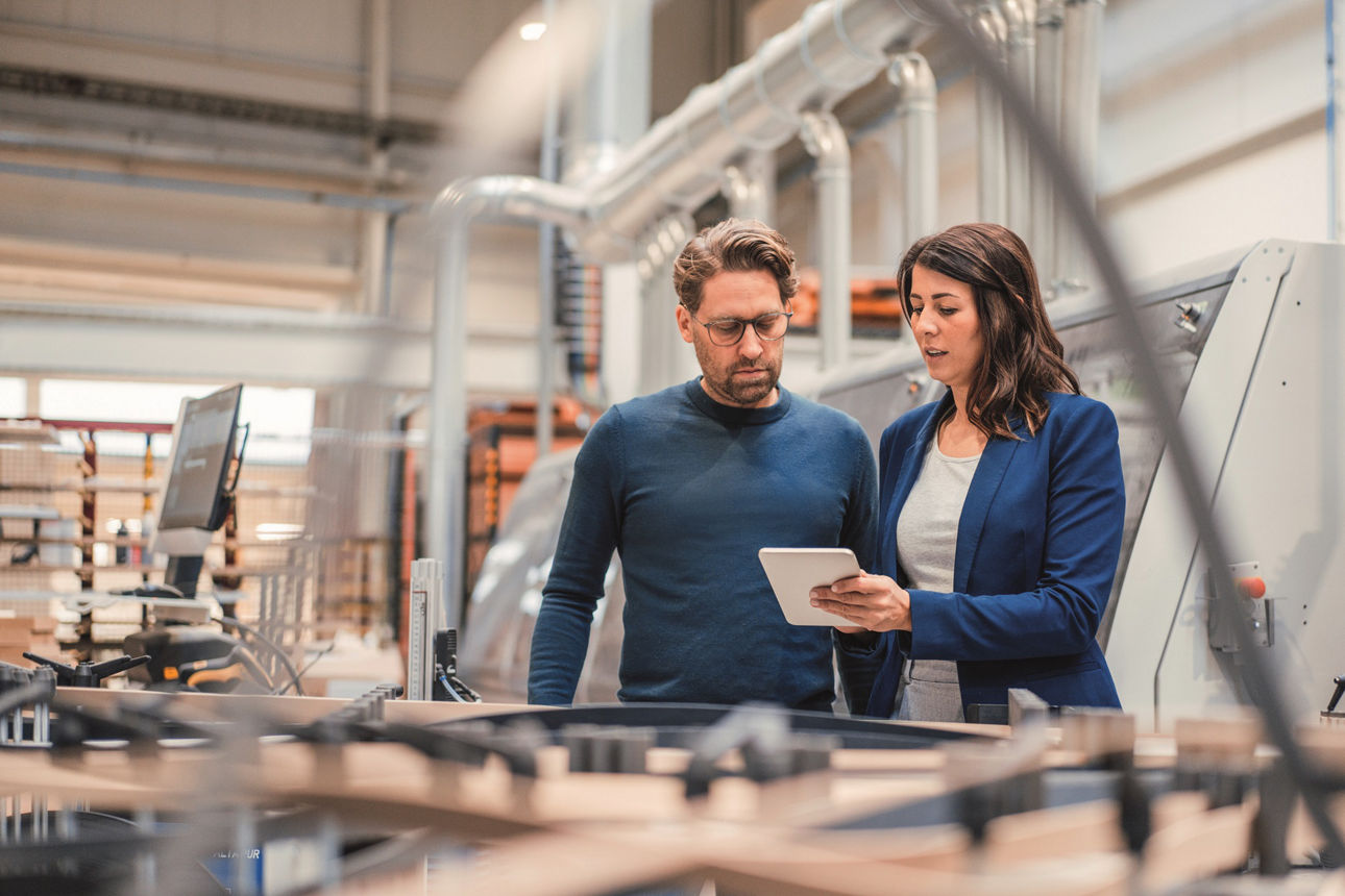 Zwei Geschäftspartner sprechen in einer Produktionshalle und sprechen