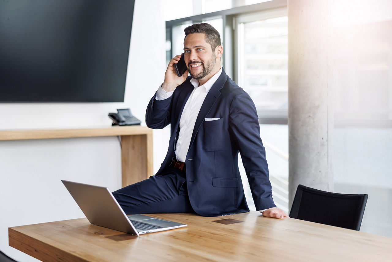 Berater im Anzug in einem Besprechungszimmer während eines Telefonats