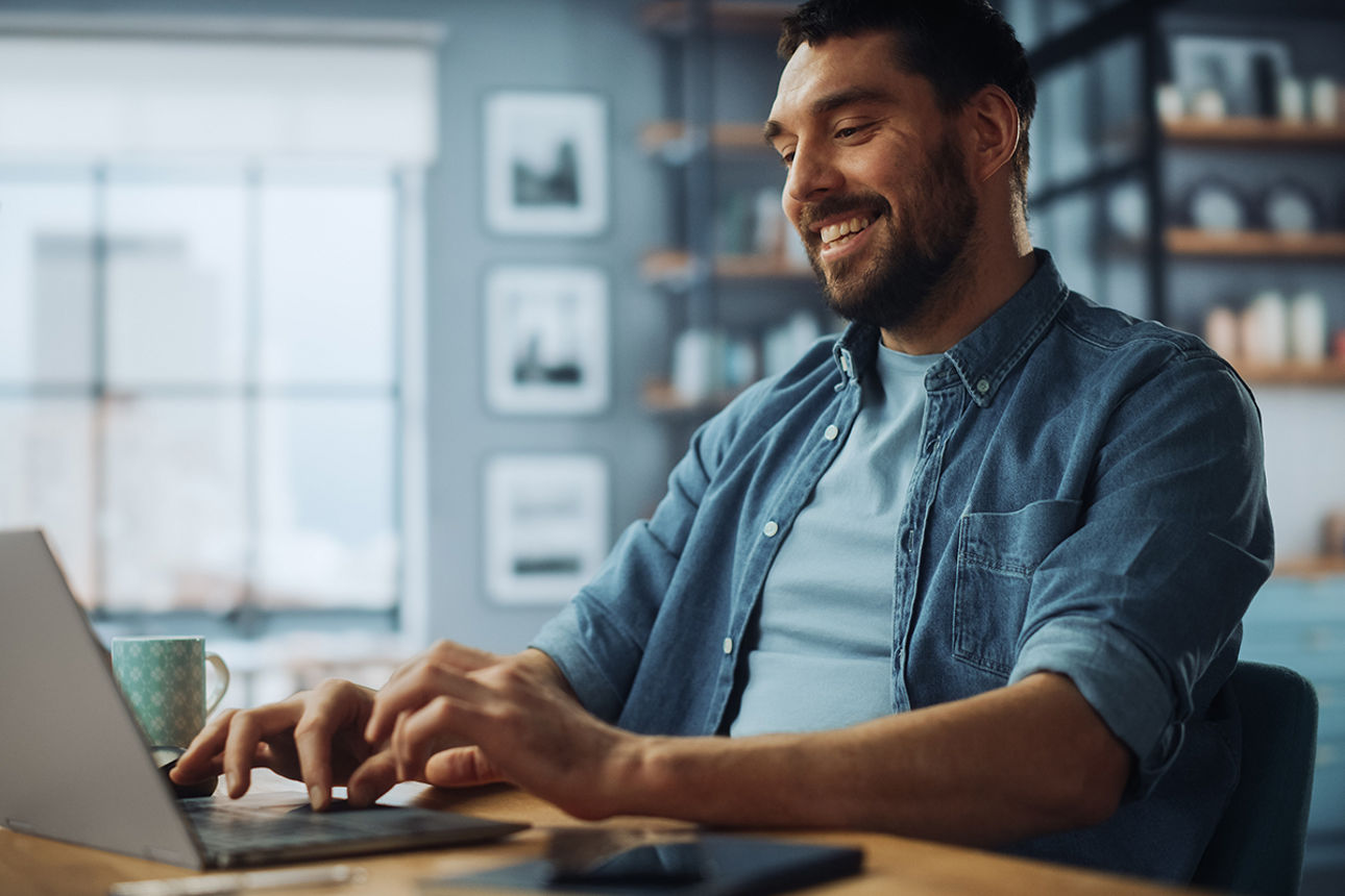 Ein Mann sitz mit Laptop am Tisch