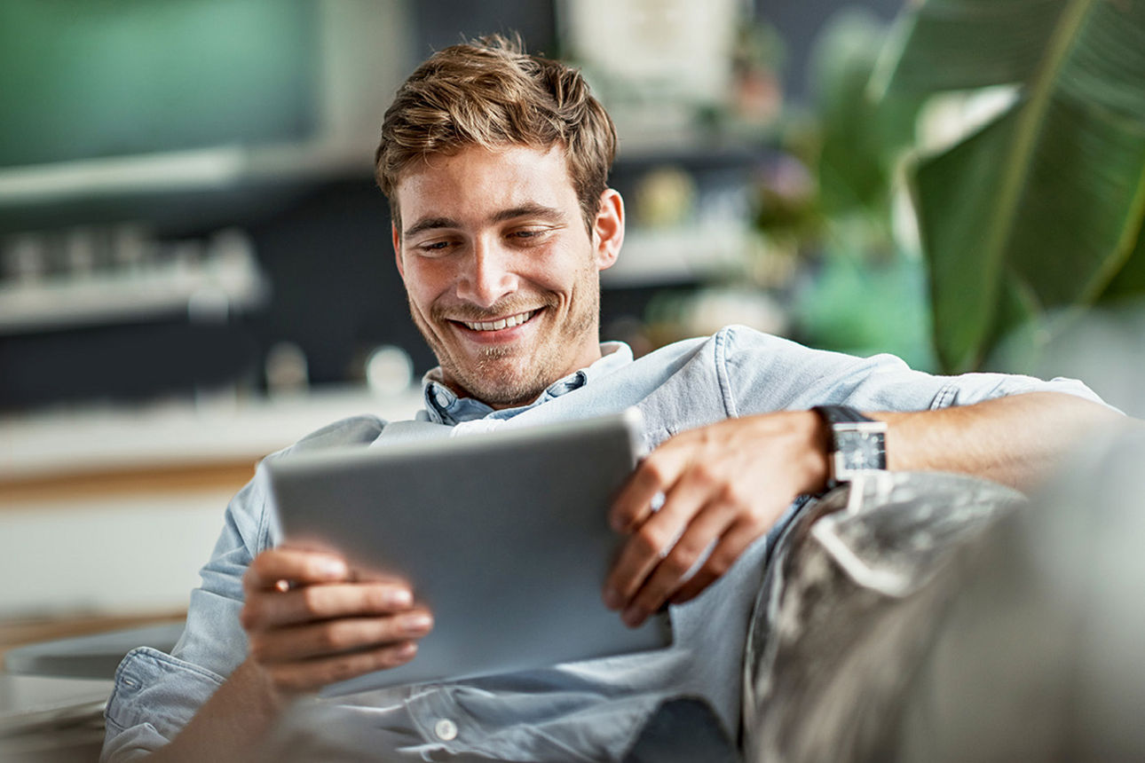 Mann schaut freudig auf Tablet