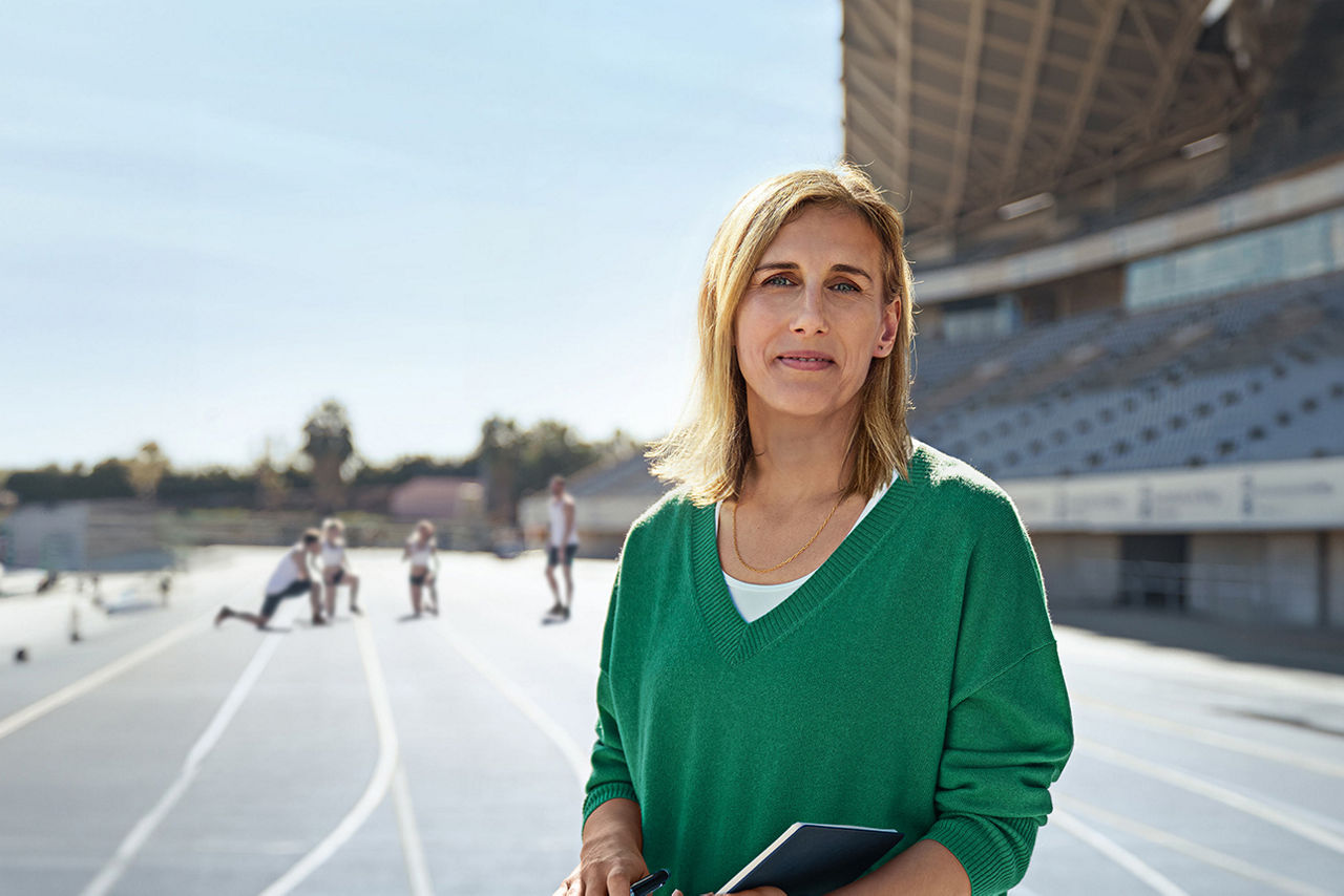 Frau steht auf 400m-Laufbahn und symbolisiert Kompetenz