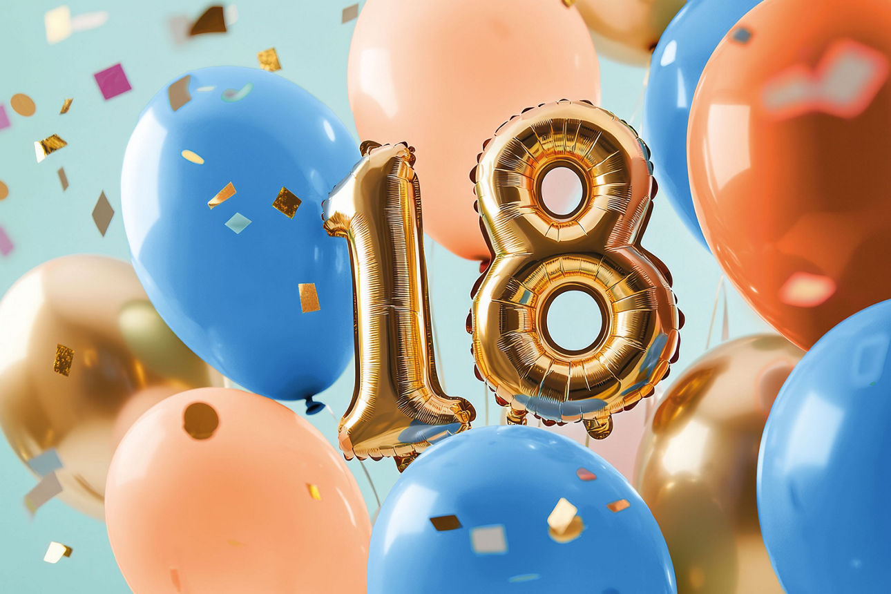 Goldene Luftballons in Form einer 18 von blauen und orangefarbenen Ballons und Konfetti umgeben