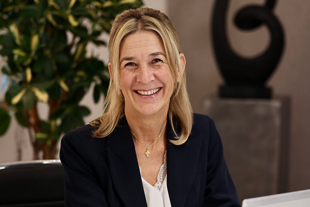 Frau sitzt im Besprechungsraum und lächelt in die Kamera