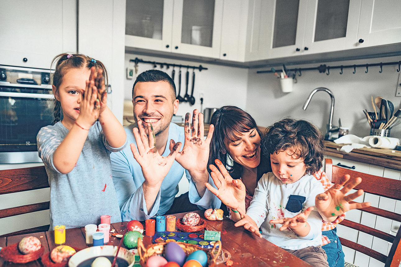 Eine Familie färbt mit zwei kleinen Kindern Ostereier.