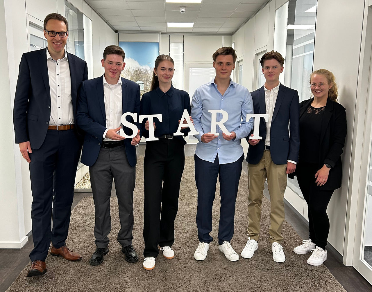 Ein Gruppenfoto, das ein neues Kapitel einläutet.  Das Wort „START“ steht im Mittelpunkt und symbolisiert den Beginn einer ne