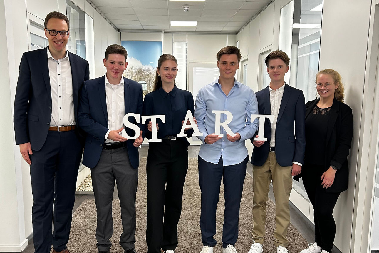Ein Gruppenfoto, das ein neues Kapitel einläutet.  Das Wort „START“ steht im Mittelpunkt und symbolisiert den Beginn einer ne