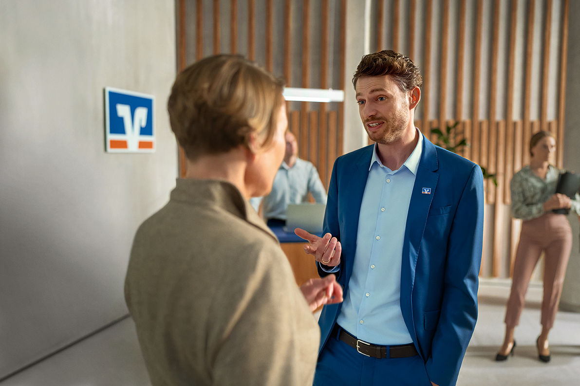 Mann und Frau unterhalten sich in Volksbank Filiale