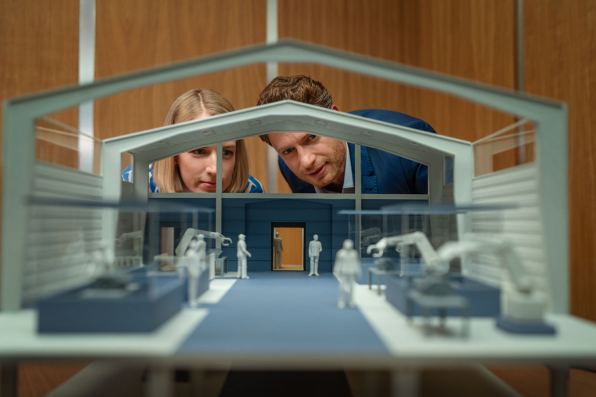 2 Personen schauen in ein Modell eines Hauses