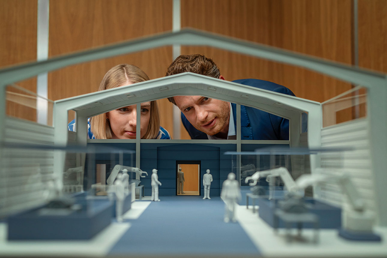 2 Personen schauen in ein Modell eines Hauses