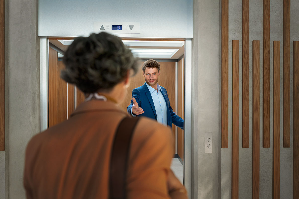 Ein Mann steht im Aufzug und hält die Tür auf