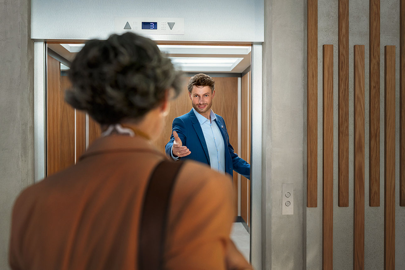 Ein Mann steht im Aufzug und hält die Tür auf