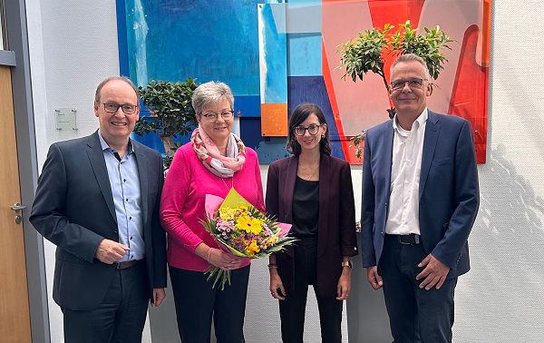 Zwei Herren und zwei Damen im Vorraum einer Filiale mit einem Blumenstrauß. 