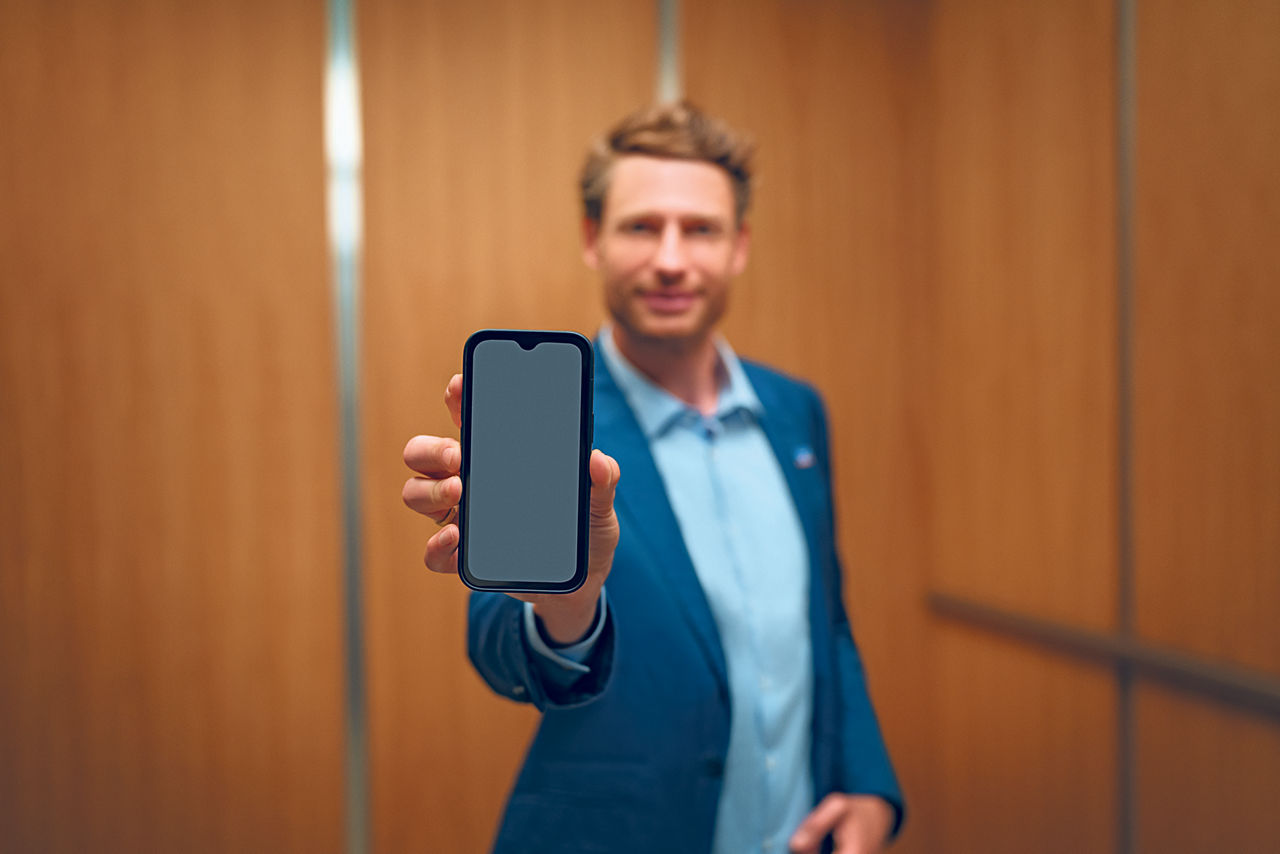 Mann im Anzug präsentiert Smartphone in der Hand