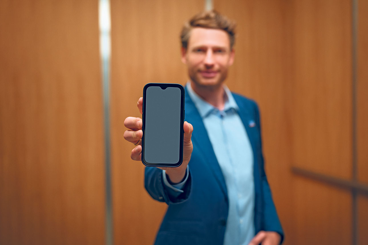 Mann im Anzug präsentiert Smartphone in der Hand