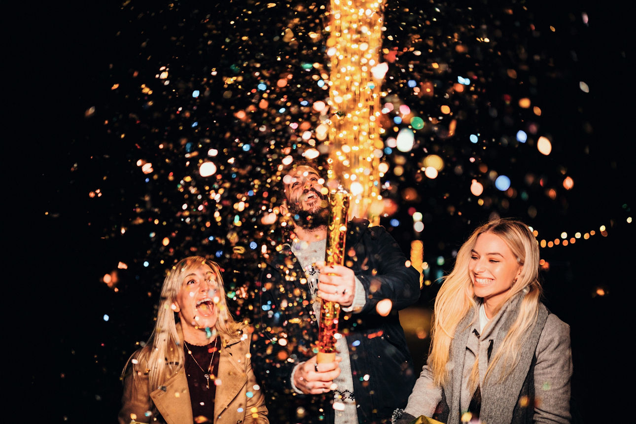 Zwei junge Frauen und ein junger Mann feiern Silvester