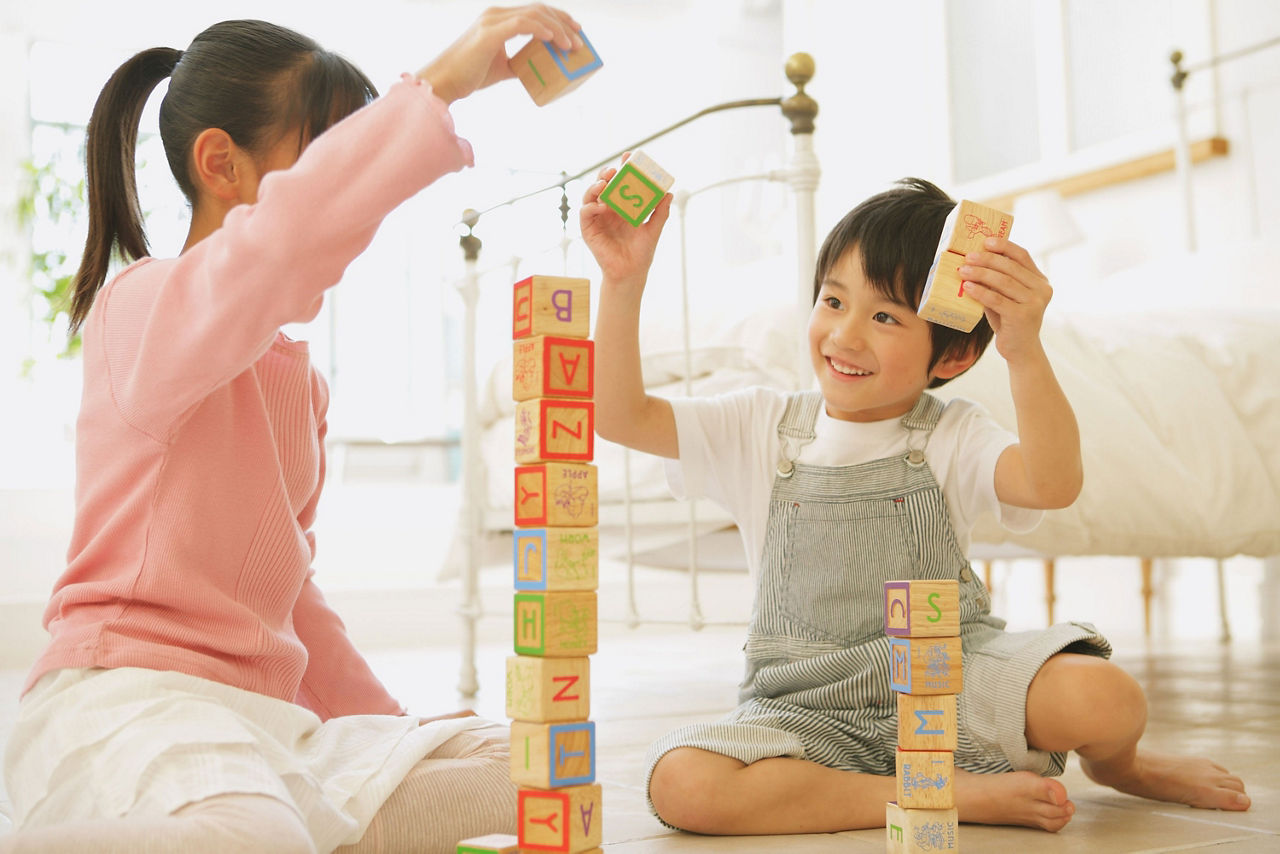 Zwei Kinder bauen mit Klötzen einen Turm