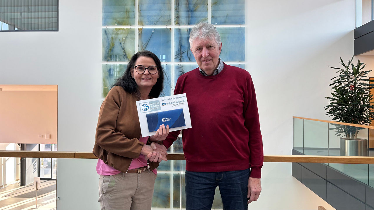 Ein Mann und eine Frau halten stolz gemeinsam eine Urkunde in einem professionellen Büro
