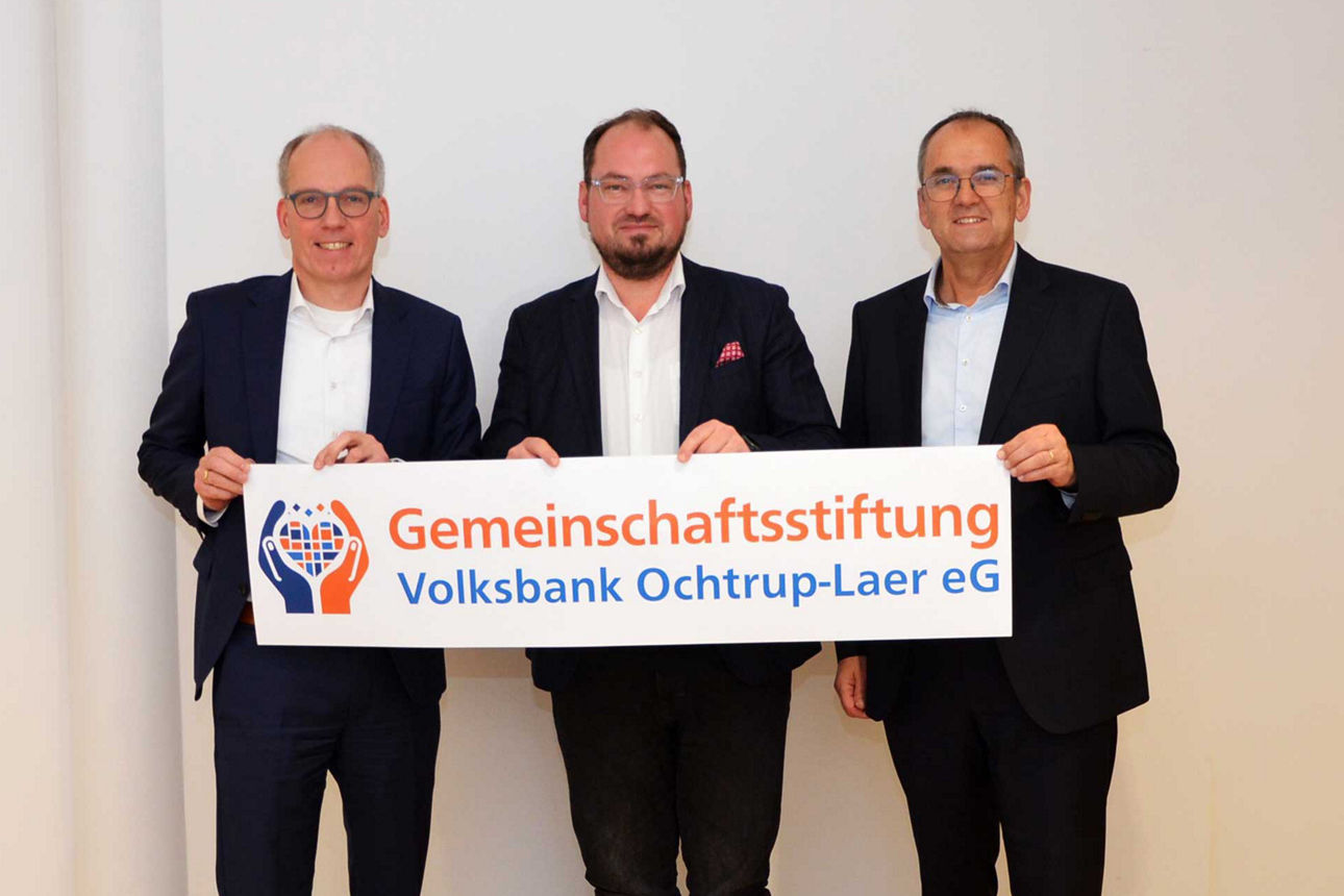 Geschäftsführender Vorstand hält Banner mit "Gemeinschaftsstiftung Volksbank Ochtrup-Laer eG" hoch.