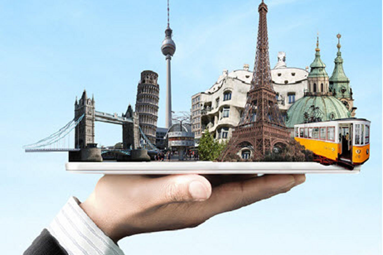 Auf einer Handfläche liegt ein Tablet, aus dem europäische Sehenswürdigkeiten vor einem blauen Himmel herausragen