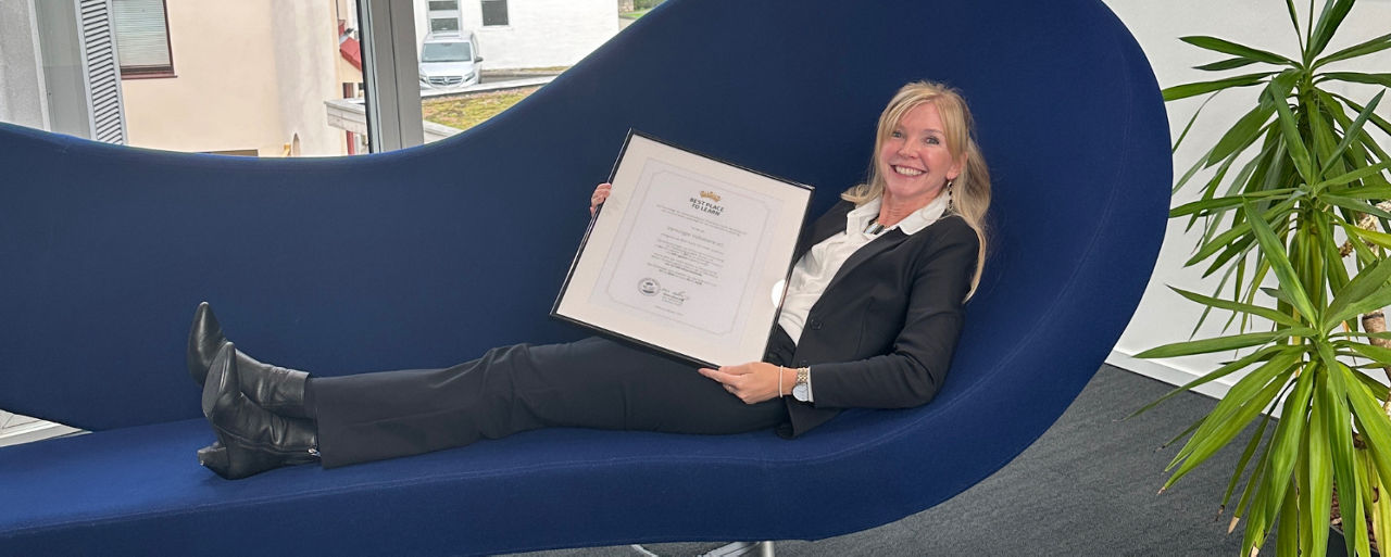 Frau in schwarzem Anzug, die sich auf einer modernen marineblauen Chaiselongue zurücklehnt