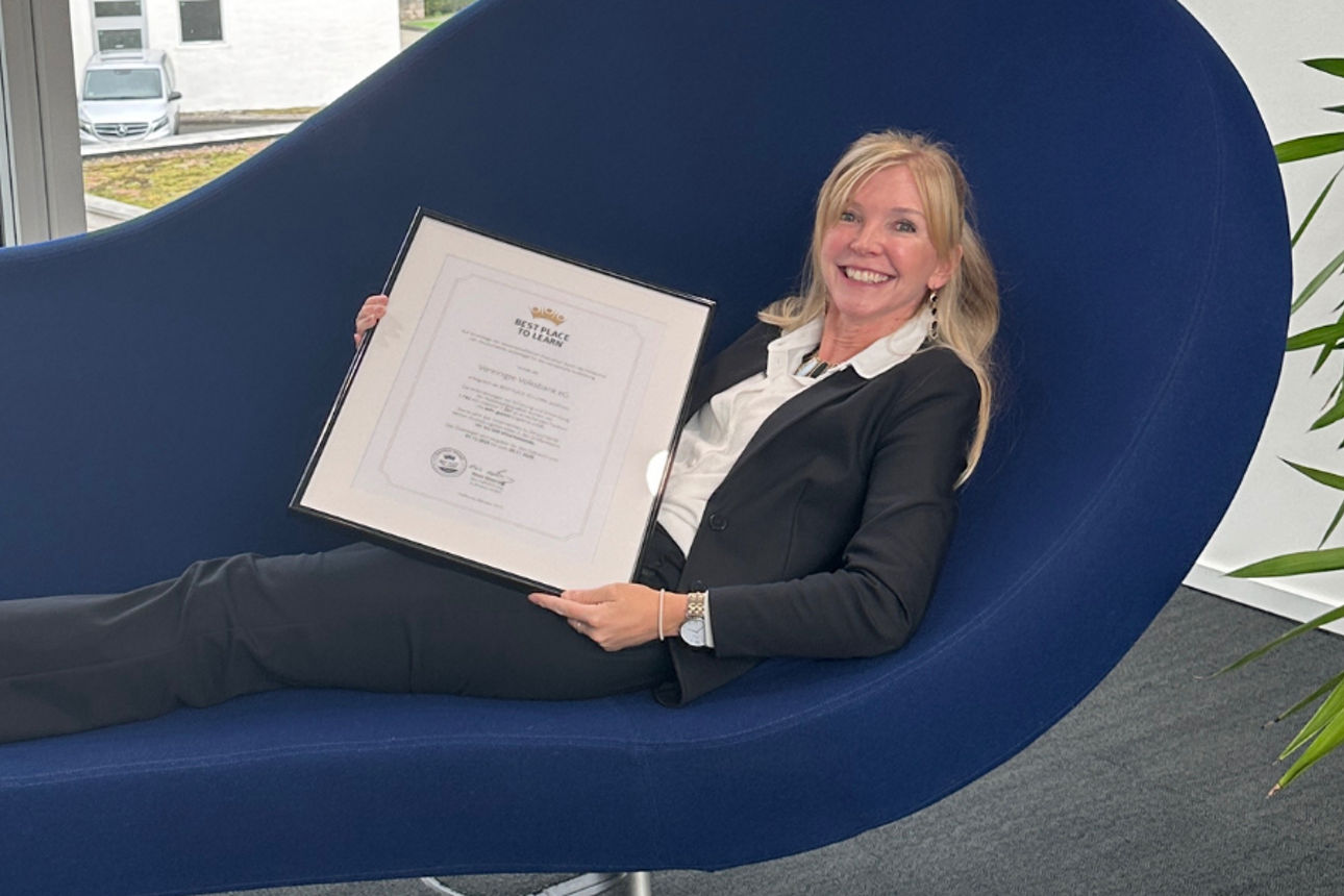 Frau in schwarzem Anzug, die sich auf einer modernen marineblauen Chaiselongue zurücklehnt