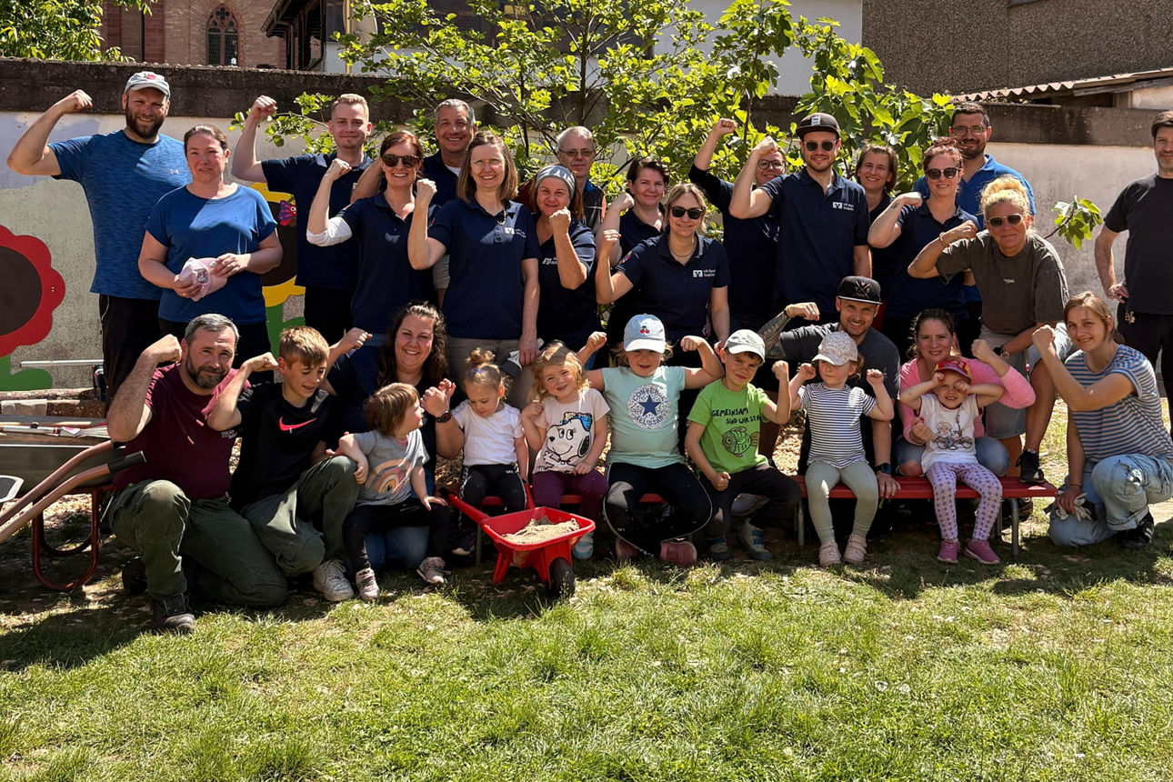 Gruppenbild vor einer Kirche, alle spannen Bizeps an
