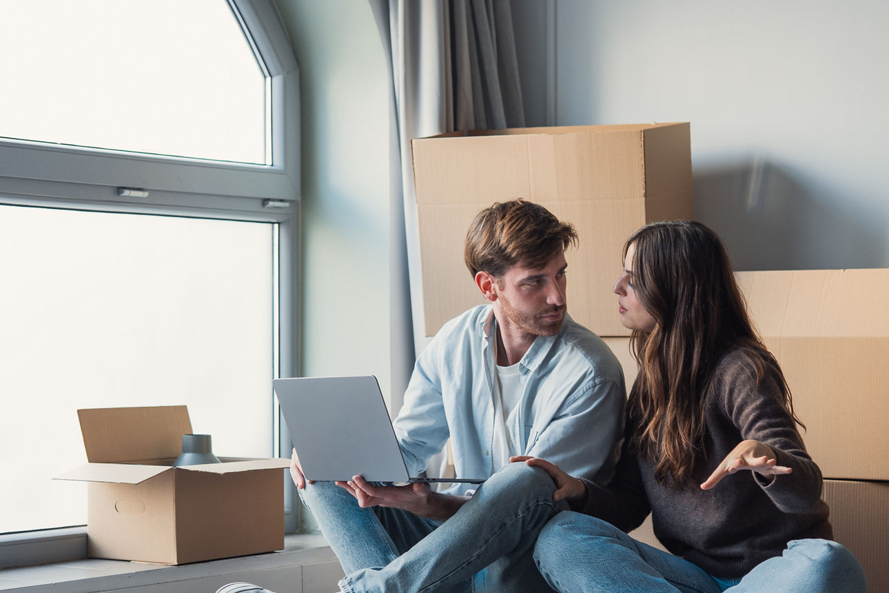 Junges Paar sitzt auf dem Boden ihrer neuen Wohnung und diskutieren